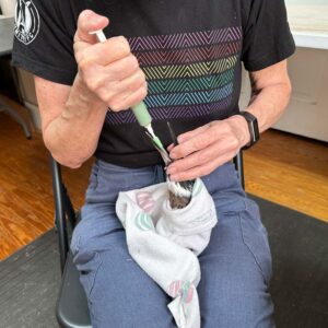 belted kingfisher wrapped in towel on wrap being syringe-fed